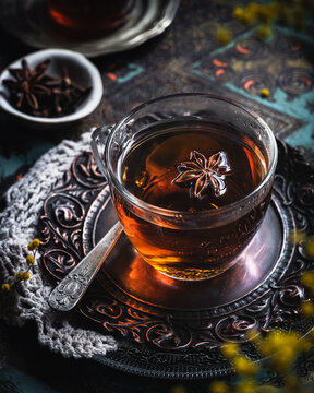 Tea with anise in a glass cup on an ornate tray