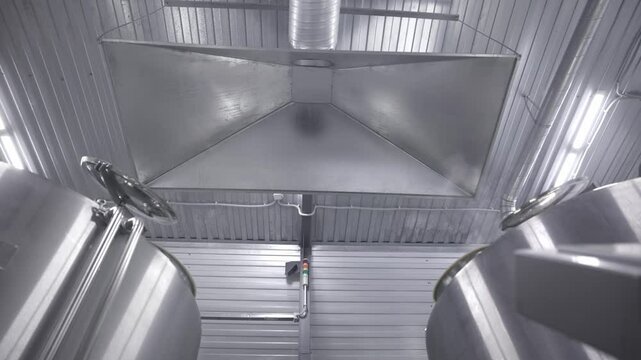 Ventilation system extraction hood supply air return for Industrial brewery facility with stainless steel fermentation tanks in modern beer factory.