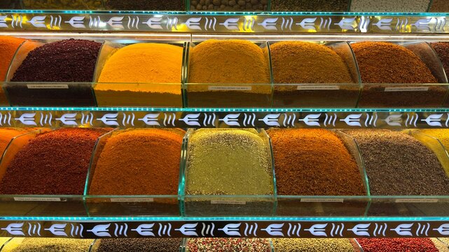 Array of vibrant oriental spices fills containers on shelf. Hues of red, yellow, and orange, colorful display. Each spice offers unique essence, flavor. Diversity of world cuisines. Food, culinary.