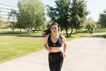 A young woman running outdoors, happy, while listening to music with headphones, Zaragoza, Spain