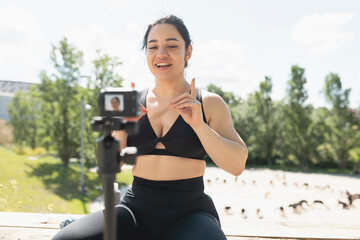 A young woman records herself on video, to explain to her followers, how to perform an exercise and sport workout