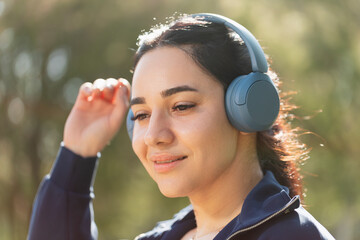 A woman relaxes and enjoys the music she listens to with her headphones, while walking and exercising in the park
