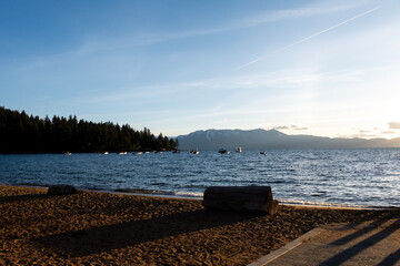 Boats Anchored in Lake Tahoe at Sunset with Forest and Mountains

