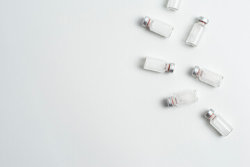 Flatlay of vaccine vial bottles with copy text space on white background. Flatlay of vaccine vials...