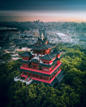 Aerial view of historic pagoda surrounded by lush forest and urban skyline, Shangcheng District, Zhejiang, People's Republic of China.