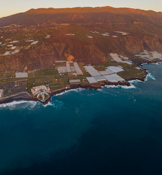 Aerial view of puerto naos town with banana fields and volcanic coastline at sunset, La Palma Island, Canary Islands, Spain.