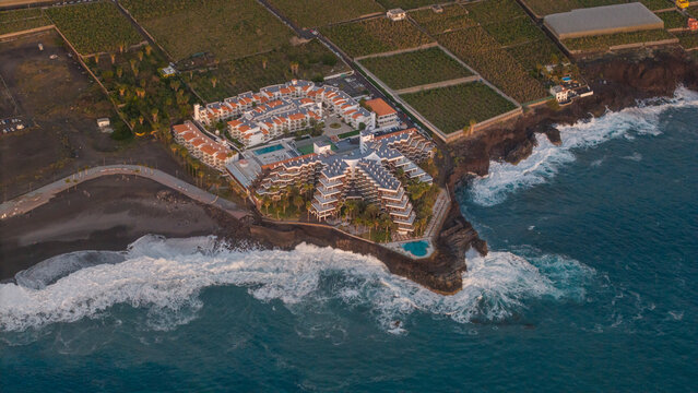 Aerial view of beautiful hotel complex by the ocean with waves crashing, Puerto Naos town, La Palma Island, Canary Islands, Spain.