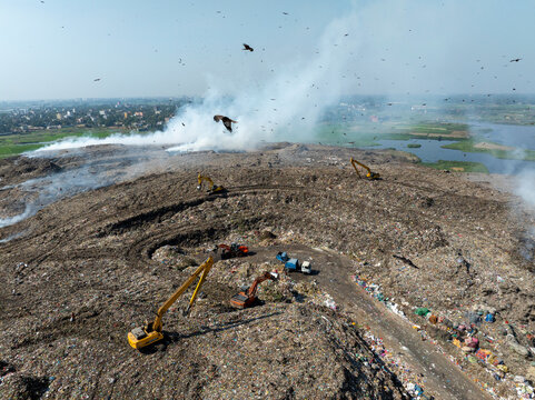 Savar, Bangladesh - 14 February 2025: Aerial view of a polluted landfill with garbage, excavators, and smoke, Banagram, Savar, Dhaka, Bangladesh.
