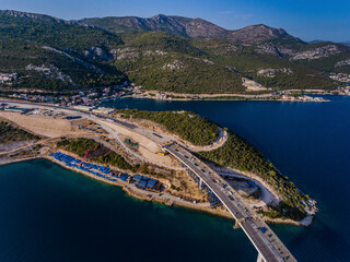 Aerial view of peljesac bridge construction site with scenic coastline and blue sky, Komarna, Croatia.