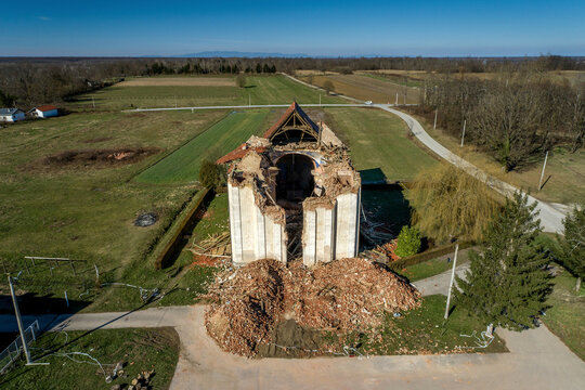 Aerial view of damaged Church of Saints Nicholas and Vitus surrounded by rubble and trees, Zazina, Croatia.