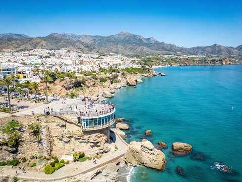 Aerial view of Balcon de Europa overlooking the beautiful coastline with azure water, cliffs, and mountains, Nerja, Malaga, Spain.