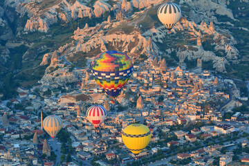 Turkey - 19 May 2025: Aerial view of colorful hot air balloons over the beautiful village of Goreme and stunning rock formations at sunrise, Cappadocia, Turkey.