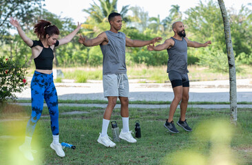Obraz premium Three friends jumping during an outdoor workout in a park