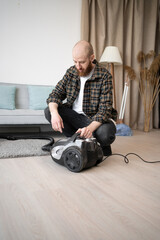 Bearded Man in Checkered Shirt Disassembling Vacuum Cleaner After Cleaning in Living Room