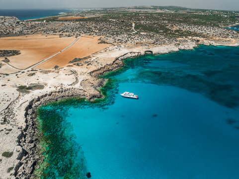 Aerial view of blue lagoon with turquoise sea and rocky shore, Cape Greco Peninsula, Famagusta, Cyprus.