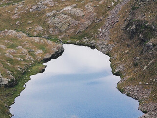 remote untouched mountain lake within rocks and reflecting the cloudy sky