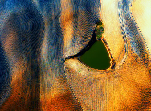 Aerial view of vibrant agricultural fields with abstract patterns and textures, Asciano, Siena, Italy.