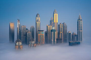 Aerial view of modern skyscrapers and luxury buildings in a vibrant cityscape surrounded by clouds, Dubai Marina, Dubai, United Arab Emirates.