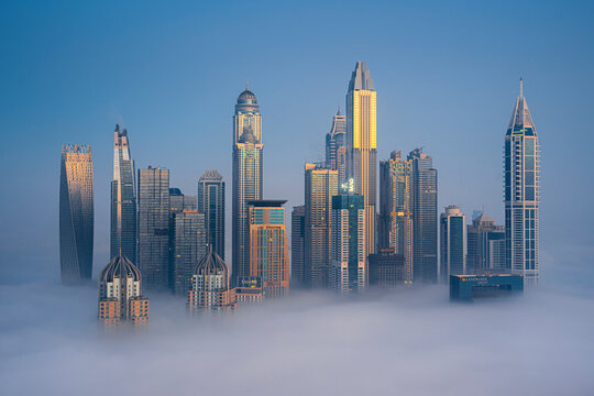 Aerial view of modern skyscrapers and luxury buildings in a vibrant cityscape surrounded by clouds, Dubai Marina, Dubai, United Arab Emirates.