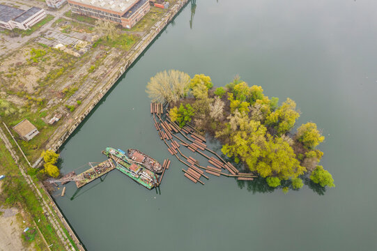 Aerial view of the serene Danube river with a tranquil island, lush trees, and a boat near an old dock, Ruse, Ruse, Bulgaria.