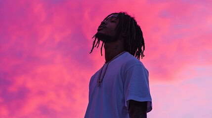 A silhouetted young man with stylish dreadlocks, wearing a black T-shirt, stands against a softly gradient pastel background.