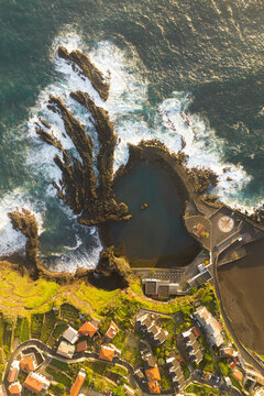 Aerial view of picturesque coastal village with homes and rocky shoreline, Madera, Portugal.