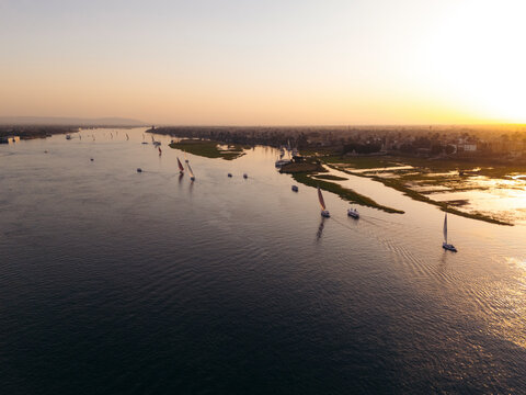 Aerial view of felucca boats sailing on the serene Nile river at sunset, Markaz al Uqsur, Luxor, Egypt.