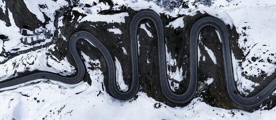 Aerial view of winding snow-covered road through beautiful alpine mountains, Julierpass, Grisons, Switzerland.