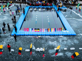 Trakai, Lithuania - 01 March 2025: Aerial view of winter swim competition on a frozen lake with swimmers and spectators, Trakai, Lithuania.