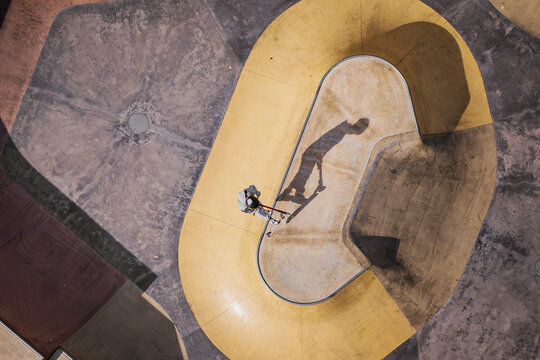 Aerial view of dynamic skateboarders in an abstract concrete skatepark with shadows and curves, Halls Head, Australia.