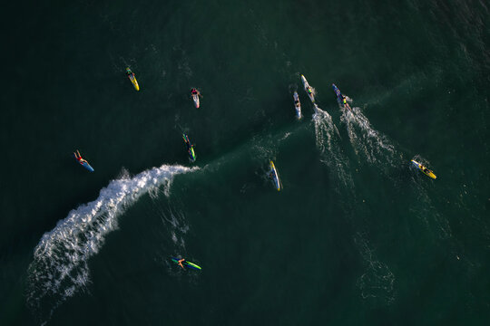 Aerial view of people on paddle boards surfing on dynamic waves in the beautiful ocean, Mandurah, Australia.