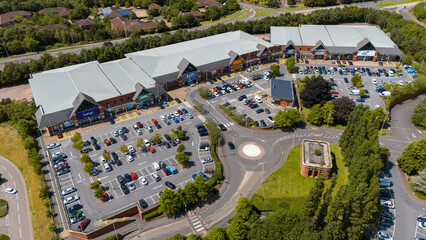 Aerial view of a busy retail park with organized stores and spacious parking lot, Exeter, United Kingdom.