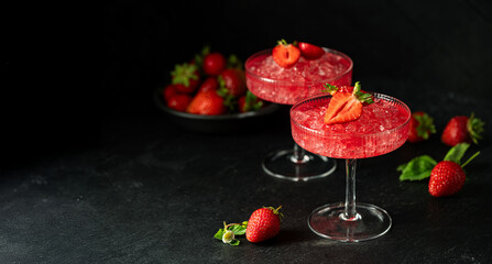 Refreshing summer drink with strawberry slices and fresh berries on dark background. Strawberry cocktail in a glass