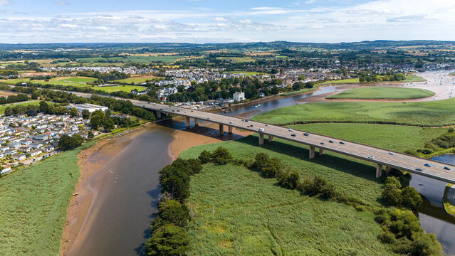 Aerial view of the M5 bridge over the serene River Exe with the charming town of Topsham and lush green fields, Devon, England.