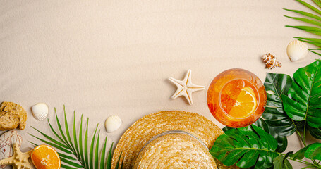 Different beach accessories, palm leaves, seashells and glass of aperol cocktail on sand, top view, flat lay. Space for text