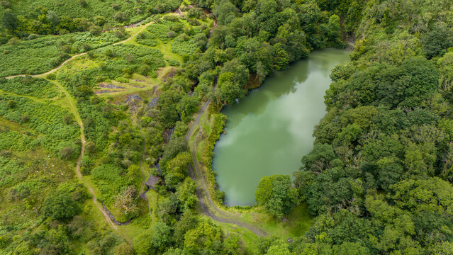 Aerial view of a serene green lake surrounded by lush forest and trees, Meldon, Okehampton, England.