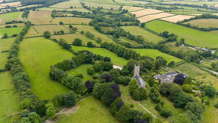 Aerial view of beautiful countryside with All Saints Church surrounded by lush fields and trees, North Tawton, Devon, United Kingdom.