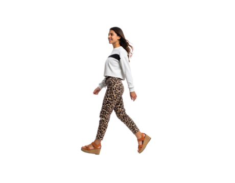 Smiling woman in leopard print pants and platform sandals walking in profile