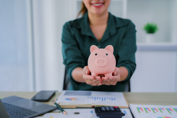 Young beautiful asian woman sitting at table and looking at growing stack of coins, financial debt employee bonus concept.