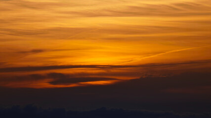 Obraz premium The sky ablaze with golden hues, where wispy clouds dance across nature's canvas in radiant splendor.