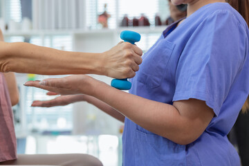 Obraz premium A female doctor is giving an elderly person dumbbells for exercise or physical therapy to make the muscles work and physical therapy also helps to restore the body to work at its full potential.