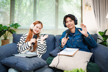 Friendly podcast hosts waving at camera with microphones and headphones