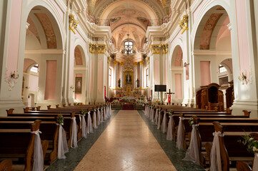 A large church with a long aisle of pews and a large altar. The pews are empty and the altar is covered in flowers