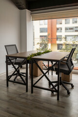 A spacious meeting room featuring tables, chairs, and a large window that fills the space with natural light, creating a bright and professional atmosphere.


