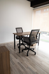 A modern private meeting room with two black chairs around a small table, enclosed by glass walls, ideal for focused conversations and collaboration.
