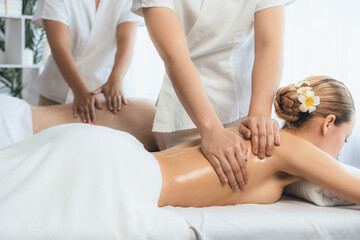 Fototapeta premium Caucasian couple customer enjoying relaxing anti-stress spa massage and pampering with beauty skin recreation leisure in day light ambient salon spa at luxury resort or hotel. Quiescent