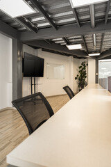 A sleek black office chair positioned beside a long white table, reflecting a modern and minimalist workspace designed for meetings and productivity.

