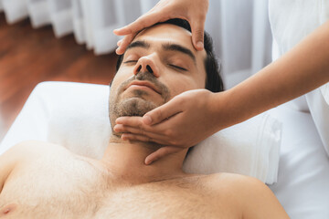 Caucasian man enjoying relaxing anti-stress head massage and pampering facial beauty skin...