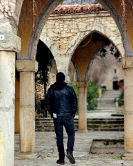 Man walking through ancient arches in historic stone courtyard