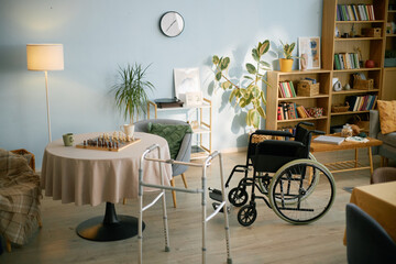 Spacious living room showcasing an inviting and warm atmosphere with a wheelchair and medical walkers near a table with a chessboard, enhancing accessibility